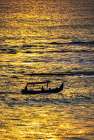 Fishing boat returning to shore in a blaze of gold sunset light in Bali, Indonesia Art Print